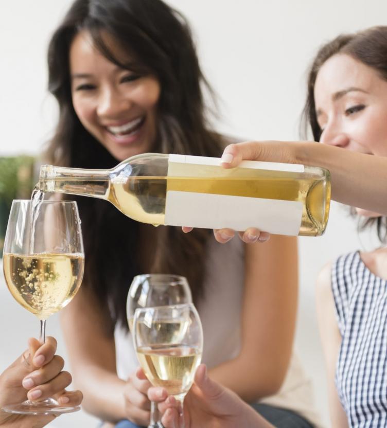 White wine being poured into a glass from glass bottle