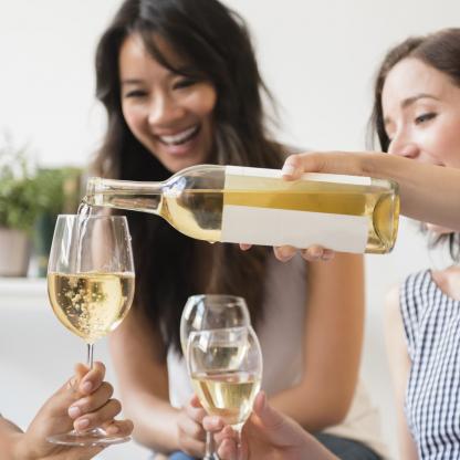 White wine being poured into a glass from glass bottle